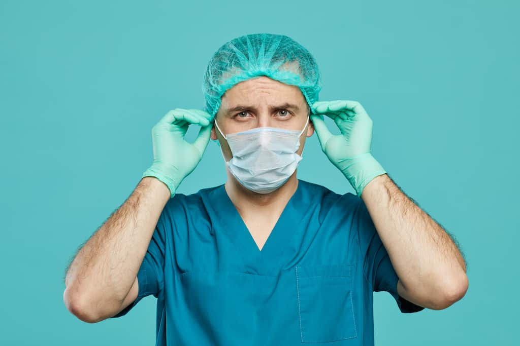 Sterile processing technician in scrubs and gloves looking at camera.